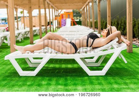 Woman Relaxing In Chaise Lounge At The Poolside. Summer Relax