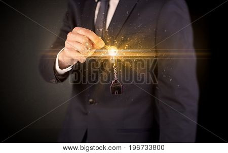 Businessman hand  over shiny keys in dark suit with dark background