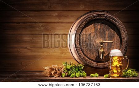Oktoberfest beer barrel and beer glass with wheat and hops on wooden table