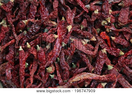 Pile of dried red chili peppers background, top view.
