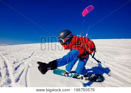 Snowboarder with a kite on fresh snow in the winter in the tundra of Russia against a clear blue sky. Teriberka, Kola Peninsula, Russia. Concept of winter sports snowkite.