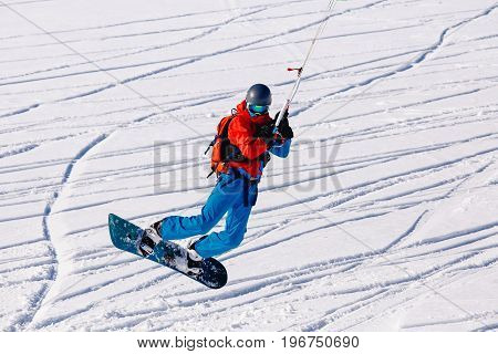 Snowboarder with a kite on fresh snow in the winter in the tundra of Russia against a clear blue sky. Teriberka, Kola Peninsula, Russia. Concept of winter sports snowkite.