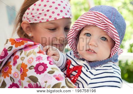 Funny cheerful baby outdoors with embracing her sister symbolizing togetherness and happiness