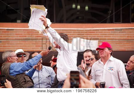 Quito, Ecuador - April 7, 2016: Closeup opposition leader Andres Paez surrounded by people and holding in his hands proofs of election fraud, police and journalists during anti government protests in Shyris Avenue.