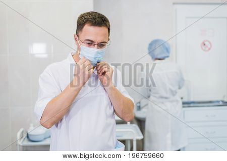 Thoughtful male surgeon wearing surgical mask in hospital.