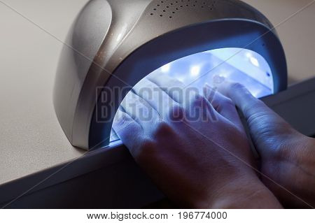 Girl dries nail Polish in a UV lamp in a beauty salon.