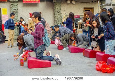 HONG KONG, CHINA - JANUARY 22, 2017: Unidentified people praying over their knees in a red soft pad inside of Wong Tai Sin Buddhist Temple to pray, in Hong Kong, China.