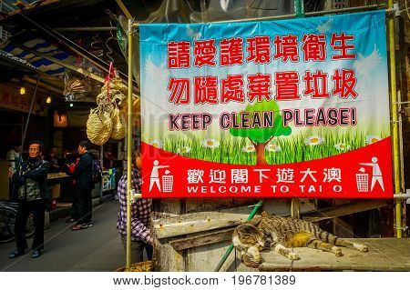 HONG KONG, CHINA - JANUARY 26, 2017: Informative sign in english and chinesse in a market in fishermen town in lantau, with a cat resting in front, in Hong Kong, China.