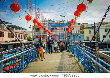 HONG KONG, CHINA - JANUARY 26, 2017: Unidentified people taking selfies over a bridge in a fishermen town in lantau, Hong Kong, China.