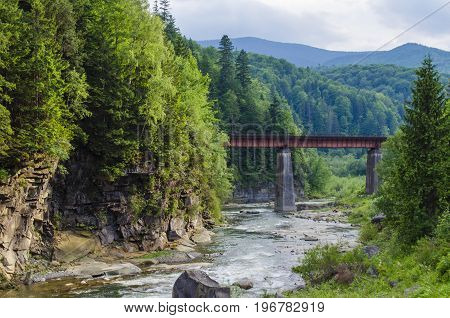 picturesque place, a mountain river with a rapid current of rocks and a bridge