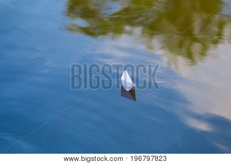 One paper boat sailing on blue water surface of lake