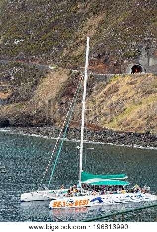 PORTO MONIZ MADEIRA PORTUGAL - SEPTEMBER 5 2016: Catamaran while sailing with tourists docked in Porto Moniz. Madeira Porttugal