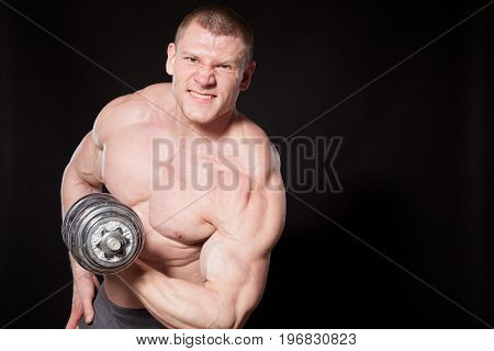 Sport the athlete bodybuilder shakes their muscles dumbbells