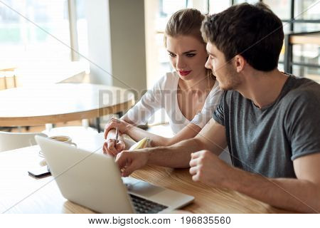 Young Couple Working On Laptop Together While Sitting At Table In Cafe