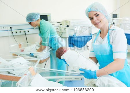 young female nurse holding a newborn baby in hospital
