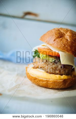 hamburger: tomato, cheese, chicken, onion, greens, on a blue wooden background. place under your account, text