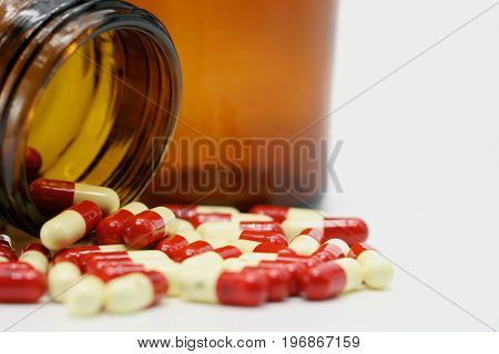 Antibiotic capsule pills with amber glass bottle on white background