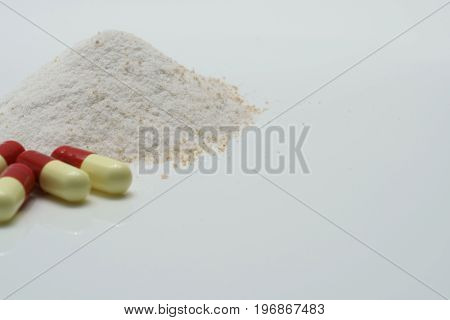 Antibiotic capsules and dry powder medicine on white background