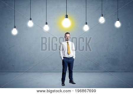 Handsome businessman in an empty space with bulbs above and uninspired face