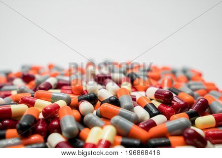 Orange black grey white red pale yellow capsule pills on white background