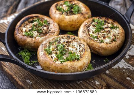 Traditional Italian Mushroom Caps stuffed with Feta as close-up in a rustic frying pan