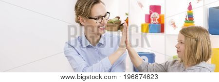 Young teacher giving little students high five for good job