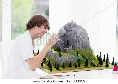 Teenager working on model building school project. Kids build miniature scale model mountain for geography class in high school. Extracurricular activities and hobby club. Art and crafts for child.