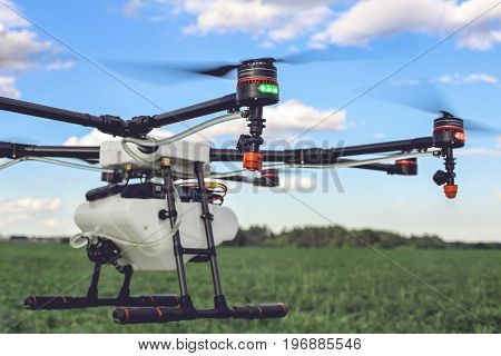 Closeup view of flying professional drone quadrocopter at the green field.