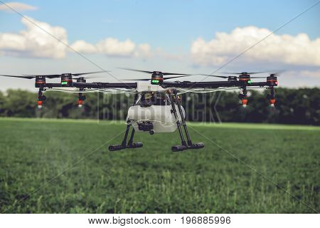 Professional large drone spray water over a green field. Agriculture industry concept drone with flying green field.