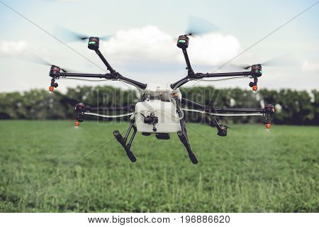 Agriculture drone spraying water or pesticides to grow over green field. Smart farming concept.