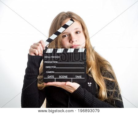 Teenage girl in black clothes blonde with long hair is holding clapperboard on white background