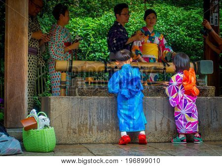 KYOTO, JAPAN - JULY 05, 2017: Young Japanese people wearing traditional Kimono and holding umbrellas in their hands in the Gion district of Kyoto, Gion is Kyoto's most famous geisha district.