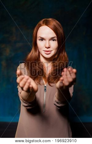 beautiful teen with red hair hold out hands to the camera and smiling