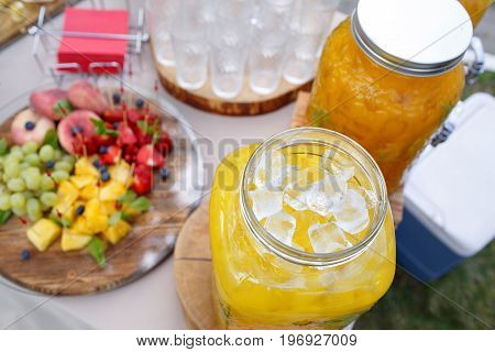 Jar of tasty fresh lemonade with ice and mint. appetizers, canapes and bruschetta on background. the fourchette in the open air. professional catering. Wedding decor