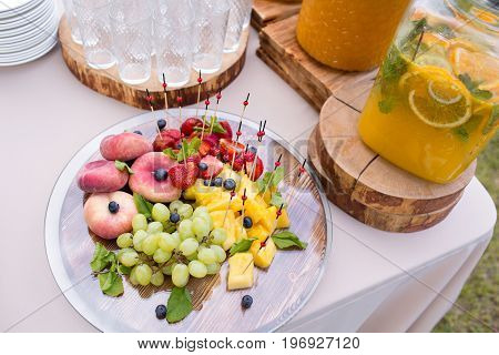 Jar of tasty fresh lemonade with ice and mint. appetizers, canapes and bruschetta, fruit on background. the fourchette in the open air. professional catering. Wedding decor