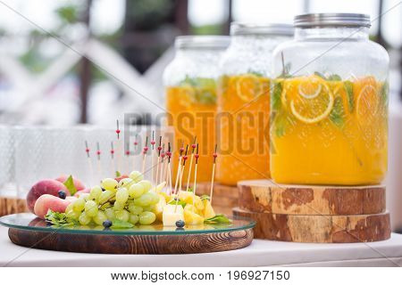 Jar of tasty fresh lemonade with ice and mint. appetizers, canapes and bruschetta, fruit on background. the fourchette in the open air. professional catering. Wedding decor