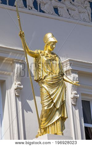 A golden statue of Athena the classical goddess of wisdom outside the famous Athenaeum Club in central London UK.