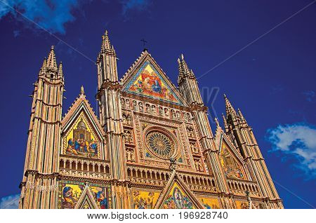 Facade details of the opulent and monumental Orvieto Cathedral (Duomo) under sunny blue sky in Orvieto, a pleasant and well preserved medieval town. Located in Umbria, central Italy. Retouched photo
