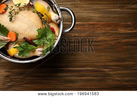 Cooking pot with turkey soaked in flavored brine on wooden table