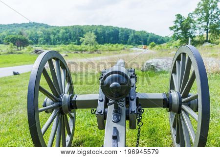 Gettysburg battlefield park with closeup of one cannon during summer and field with road