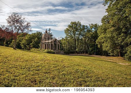 Bomarzo, Italy - May 20, 2013. View of stone small temple and gate at sunset amidst the vegetation in the Park of Bomarzo, also known as Park of Monsters, near Viterbo. Located in the Lazio region, central Italy