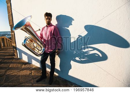 Musician with tuba near the white wall the shadow of the tool.