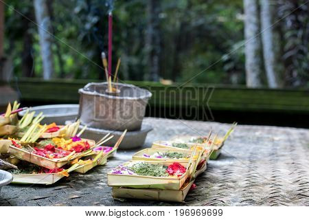 Traditional balinese offerings to gods in Bali with flowers and aromatic sticks. Bali.