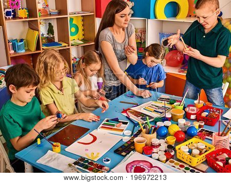 Plasticine modeling clay in children class. Teacher teaches kids together play dough and mold from plasticine in kindergarten or preschool. Preparation for exhibition of animals from plasticine.
