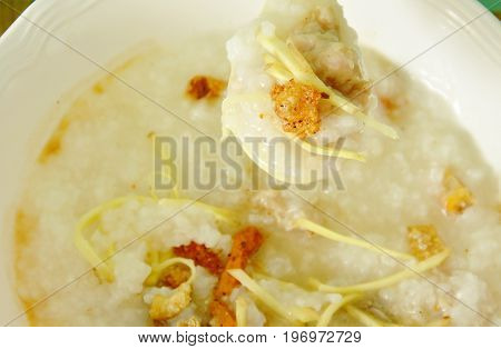 boiled rice with minced pork and slice ginger on plastic soup spoon