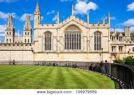 Oxford United Kingdom - June 20 2006: All Souls College (The Warden and the College of the Souls of All Faithful People Deceased in the University of Oxford) is a constituent college of the Oxford University. Students are talking at the fence of Radcliffe