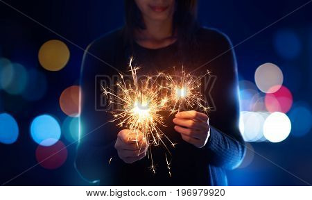 Female playing sparklers during celebration - Bokeh Background
