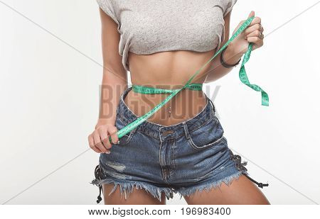 Weight losing - measuring woman's body. Sexy woman ass in jeans shorts.