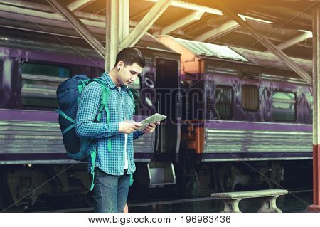 Hipster smart man with looking tablet screen waiting at train station.