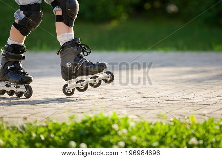 Closeup view of black roller skates or rollerblading. Roller skate legs of a child in the park. Boy's legs in roller blades.